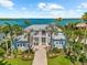 Stunning waterfront home with lush landscaping and a gray metal roof offering picturesque views of the bay at 757 Hideaway Bay Dr, Longboat Key, FL 34228