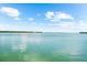 Beautiful, serene water view featuring glistening water, lush greenery, and a clear blue sky with fluffy white clouds at 757 Hideaway Bay Dr, Longboat Key, FL 34228
