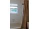 A clean bathroom with a standard tub and shower combination, featuring a brown shower curtain and small window at 13811 Waterthrush Pl, Lakewood Ranch, FL 34202