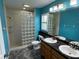 Bathroom with teal walls, double sinks, and glass block shower at 5009 Sturbridge Ct, Sarasota, FL 34238