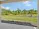 Expansive backyard with lush greenery, a pond, and mature trees view from the lanai at 305 Potenza Loop, Nokomis, FL 34275