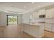 Open-concept kitchen with white cabinets, stainless steel appliances, and wood-look flooring at 305 Potenza Loop, Nokomis, FL 34275
