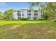 Exterior view of a bright white multi-story condo with a well-maintained lawn and mature trees at 6304 Pointe West Blvd # A102, Bradenton, FL 34209