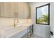 Clean laundry room with a farmhouse sink and ample storage at 111 Gull Dr, Anna Maria, FL 34216