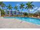 Community pool with a brick deck, palm trees, lounge chairs, and an apartment complex in the background at 280 Hidden Bay Dr # 203, Osprey, FL 34229