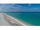 A beautiful, wide sandy beach with crystal-clear turquoise water under a blue sky with scattered clouds at 280 Hidden Bay Dr # 302, Osprey, FL 34229