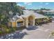Inviting yellow clubhouse featuring an arched entrance, metal roof, and lush tropical landscaping at 280 Hidden Bay Dr # 302, Osprey, FL 34229