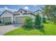 Two-car garage, paver driveway, and landscaped lawn with lush greenery at 100 Corserra Dr, Nokomis, FL 34275