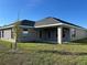 Backyard showcasing a covered patio, spacious lawn, and modern home design at 2600 Averland Loop, North Port, FL 34287