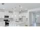 A bright kitchen with white cabinets, a quartz island, modern pendant lights, and stainless appliances at 1580 Laurel Brook Ln, Port Charlotte, FL 33953