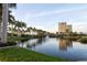 Picturesque view of the pond with a fountain, tropical landscaping, and a condominium building in the background at 611 Riviera Dunes Way # 108, Palmetto, FL 34221