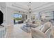 Spacious living room with light leather furniture, a large TV, and sliding doors leading to the pool at 13853 Siena Loop, Lakewood Ranch, FL 34202