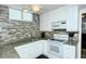 Modern kitchen with white cabinets, granite counters, and tiled backsplash at 100 Sands Point Rd # 324, Longboat Key, FL 34228