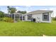 Lush backyard featuring an enclosed screened in pool area, palm trees, and manicured lawn at 2511 Stagnaro Rd, North Port, FL 34287