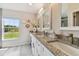Bathroom with a granite countertop vanity, dual sinks, and scenic outdoor views at 2511 Stagnaro Rd, North Port, FL 34287