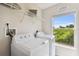 Bright laundry room featuring a washer, dryer, shelving, and a large window at 2511 Stagnaro Rd, North Port, FL 34287