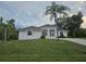 Inviting single-story home featuring a lush green lawn and mature palm trees enhancing its curb appeal at 15 Tee View Pl, Rotonda West, FL 33947
