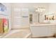 Bright bathroom with white cabinets, neutral countertop, and jacuzzi tub with window blinds at 7249 Orchid Island Pl, Bradenton, FL 34202