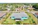 Aerial view of a house with a gray roof and an adjacent community filled with mature trees at 1415 Piedmont Rd, Venice, FL 34293