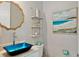 Stylish bathroom featuring blue glass vessel sink, accent shelves, and beach-themed artwork at 149 Mckinley Dr, Sarasota, FL 34236