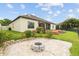 Well-maintained backyard featuring a patio, fire pit, lush landscaping, and a partial view of a screened-in porch at 6309 75Th E Ave, Palmetto, FL 34221