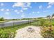 Backyard features a green lawn, a decorative fire pit, a secure fence, and tranquil lake views at 6309 75Th E Ave, Palmetto, FL 34221