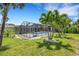 The fenced backyard features a screened-in pool and patio area, all surrounded by tropical landscaping at 701 Armada S Rd, Venice, FL 34285