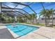 A screened in pool with a travertine tile deck and lush landscaping creates a private backyard oasis at 701 Armada S Rd, Venice, FL 34285
