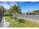 Landscaped backyard with palm trees, a privacy fence, and a grassy area at 701 Armada S Rd, Venice, FL 34285