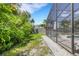 Screened pool and grassy area with tropical landscaping at 701 Armada S Rd, Venice, FL 34285