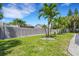 Spacious backyard with grassy lawn, palm trees, and a privacy fence at 701 Armada S Rd, Venice, FL 34285