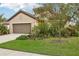 Tan house with brown garage door, landscaping, and driveway at 308 Cassano Dr, Nokomis, FL 34275