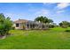 Expansive backyard with lush grass, palm trees, and screened patio, perfect for relaxation at 310 Lake Tahoe Ct, Englewood, FL 34223