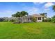 Well-maintained backyard with lush green grass, tropical landscaping, and a screened-in pool area at 310 Lake Tahoe Ct, Englewood, FL 34223