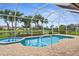 Backyard oasis featuring a screened-in pool, a hot tub, a beautiful lake view and tropical landscaping at 310 Lake Tahoe Ct, Englewood, FL 34223