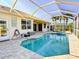 Screened-in pool and spa area featuring brick pavers, lush landscaping, and sunny skies at 310 Lake Tahoe Ct, Englewood, FL 34223