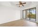 A bedroom with wood floors, a ceiling fan, and a sliding door leading to a balcony at 7718 Lake Vista Ct # 405, Lakewood Ranch, FL 34202