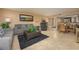 Open living room with grey couch, tiled floors, and a view into the dining area at 5920 Midnight Pass Rd # 104, Sarasota, FL 34242