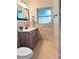 Bright bathroom featuring a wood vanity with marble top and beige tiled floor and walls at 3637 Mineola Dr, Sarasota, FL 34239