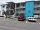 Exterior view of a condominium building with blue accents, parking space, two cars, and staircase on the side at 5906 Garden Ln # A22, Bradenton, FL 34207