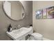 Powder room with gray tile, round mirror, and artwork at 12014 Perennial Pl, Lakewood Ranch, FL 34211
