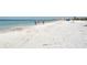 Beachgoers stroll along a wide, white sand beach with calm ocean waters at 1300 N Portofino Dr # 305, Sarasota, FL 34242