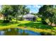 Beautiful backyard featuring a screened-in pool, lush green lawn, and a serene pond view at 7430 Weeping Willow Dr, Sarasota, FL 34241