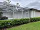 Backyard showcasing a screened-in pool area with white hurricane shutters, surrounded by lush landscaping and green lawn at 7430 Weeping Willow Dr, Sarasota, FL 34241