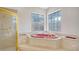 Bathroom with jetted tub and shower with luxurious finishes, gold fixtures, and natural light at 7430 Weeping Willow Dr, Sarasota, FL 34241