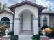 Close-up of home featuring an arched entryway, complemented by decorative plants and manicured landscaping at 7430 Weeping Willow Dr, Sarasota, FL 34241