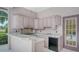 Covered outdoor kitchen features pink cabinetry, sink, tile countertops, and views of the lake at 7430 Weeping Willow Dr, Sarasota, FL 34241