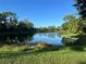 Scenic view of a calm pond reflecting the clear blue sky, framed by verdant trees and vegetation at 7430 Weeping Willow Dr, Sarasota, FL 34241