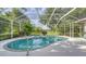 Screened-in pool and jacuzzi overlook the beautiful backyard, foliage, and water view at 7430 Weeping Willow Dr, Sarasota, FL 34241