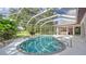 Screened-in pool and jacuzzi overlook the well-manicured backyard, foliage, and water view at 7430 Weeping Willow Dr, Sarasota, FL 34241